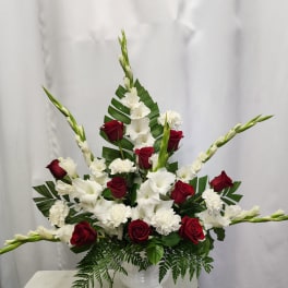 Red roses and white gladiolus arranged in a white vase
