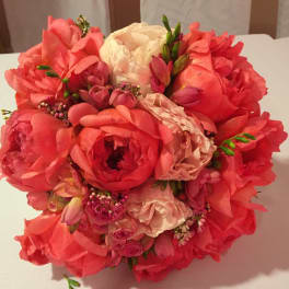 Round bouquet of coral and blush flowers with white blooms