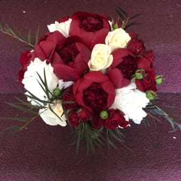 Red and white rose bouquet with dark foliage on a purple carpet