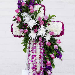 Large floral cross arrangement with pink roses, white chrysanthemums, and purple orchids