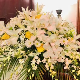 Large white and yellow floral arrangement with lilies and orchids