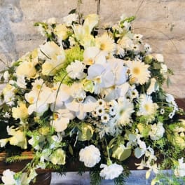 Large white floral arrangement with orchids and daisies on a table