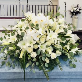 Large white floral casket spray with lilies and orchids