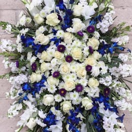 Large white and blue funeral spray on a stand