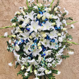 Large white floral spray with lilies and orchids on a tan wall
