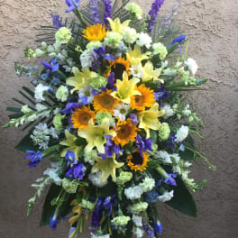 Standing floral spray with sunflowers, lilies, and purple blooms