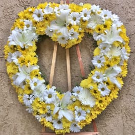 Heart-shaped floral wreath with white lilies and yellow and white daisies