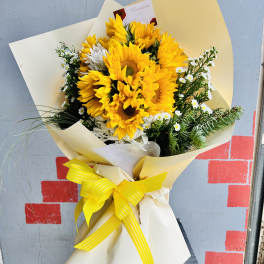 Bouquet of yellow sunflowers with white filler flowers in cream wrapping
