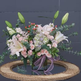 Bouquet of white lilies, pink roses, and hydrangea in a glass vase