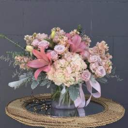 Pink and blush floral arrangement in a glass vase with a ribbon