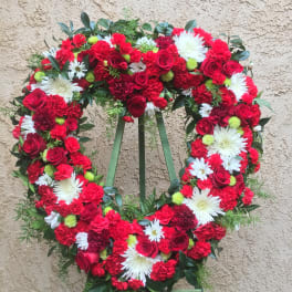 Heart-shaped floral wreath with red roses, red carnations, and white daisies