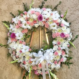 Heart-shaped floral wreath with pink and white flowers on a wooden stand