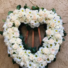 Heart-shaped floral wreath of white roses and daisies on an easel