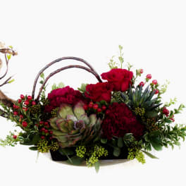 Red roses and burgundy blooms in a low basket with branches and berries