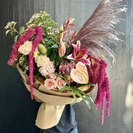 Large bouquet with pink lilies, roses, and pampas grass wrapped in paper