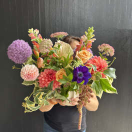 Large mixed bouquet with dahlias, roses, and purple allium in a white vase