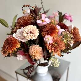 Bouquet of orange, pink, and cream flowers in a white vase