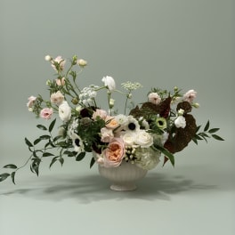 Mixed pastel floral arrangement in a white pedestal vase