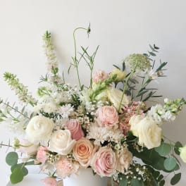 Pastel bouquet of roses, ranunculus, and white blooms in a white vase