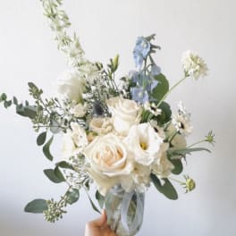 White and pale blue bouquet in a glass jar vase
