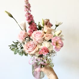 Pink and white bouquet in a glass vase with a pink ribbon