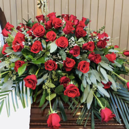Large arrangement of red roses with greenery in a wooden casket spray