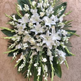 White lily and snapdragon floral spray with dark green foliage