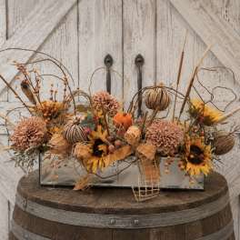 Autumn floral arrangement in a rectangular glass vase with pumpkins and sunflowers