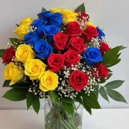 Bouquet of red, yellow, and blue roses in a clear glass vase