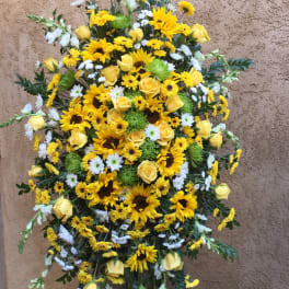 Standing spray of yellow roses, sunflowers, and white daisies