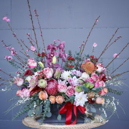 Large floral arrangement with pink, white, and peach blooms in a black container