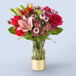 Mixed pink and red flowers arranged in a clear glass vase