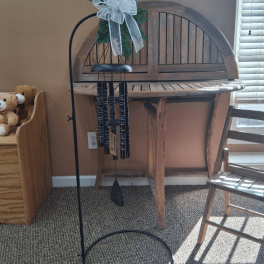 Green wind chime with a white bow on a black stand