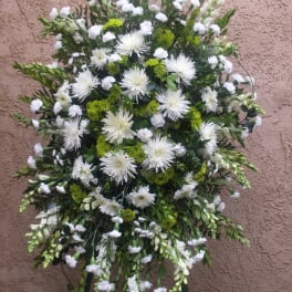 Large white and green funeral spray on a stand