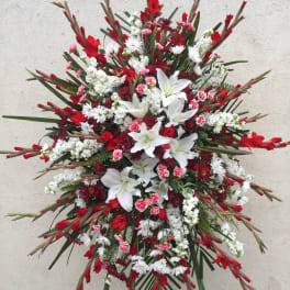 Large red, white, and pink funeral spray with lilies and daisies