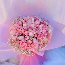 Pink rose bouquet with carnations and baby's breath wrapped in pastel paper