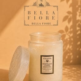 Glass jar candle with a decorative lid on a warm beige background