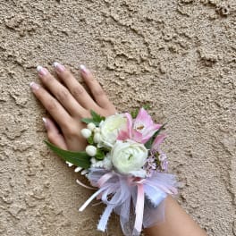 Pink and white wrist corsage with ribbon on a hand