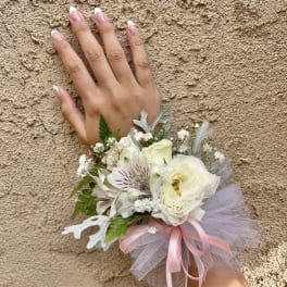 Small white floral wrist corsage with pink ribbon and tulle