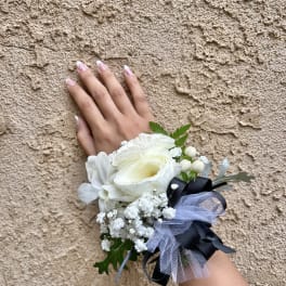 White wrist corsage with ribbon and small berries on a hand