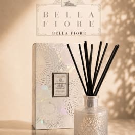 A reed diffuser in a patterned glass bottle with a matching box