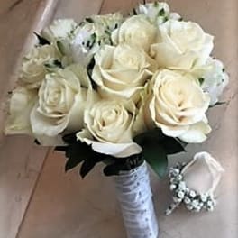 Bridal hand-tied bouquet of ivory roses with wrapped handle and matching single-rose boutonniere.