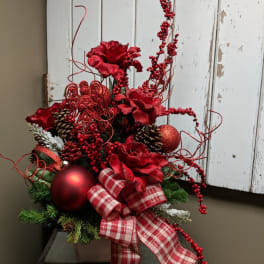 Red floral holiday arrangement with plaid ribbon, pinecones, and ornaments