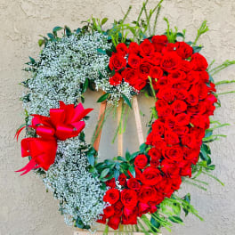 Heart-shaped red rose wreath with white baby's breath and a red bow