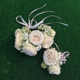 Cream rose floral wrist corsage with pink ribbon on green grass