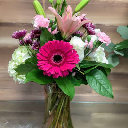 Bouquet of pink lilies, gerbera daisies, and mixed blooms in a glass vase