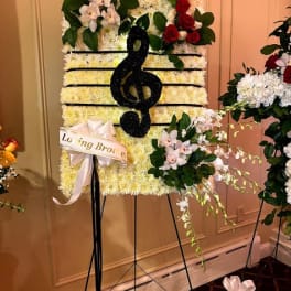 Standing floral tribute with a black treble clef on a white flower panel