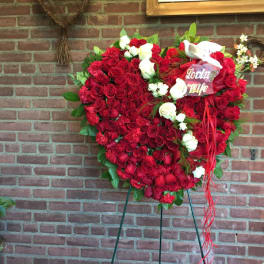 Heart-shaped red rose arrangement with white roses and a ribbon on an easel