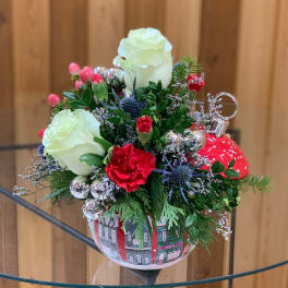 Holiday floral arrangement in a red ornament-shaped container with white roses and red carnations