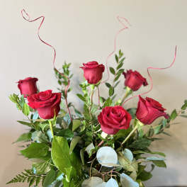 Bouquet of red roses with greenery and curly ribbon accents
